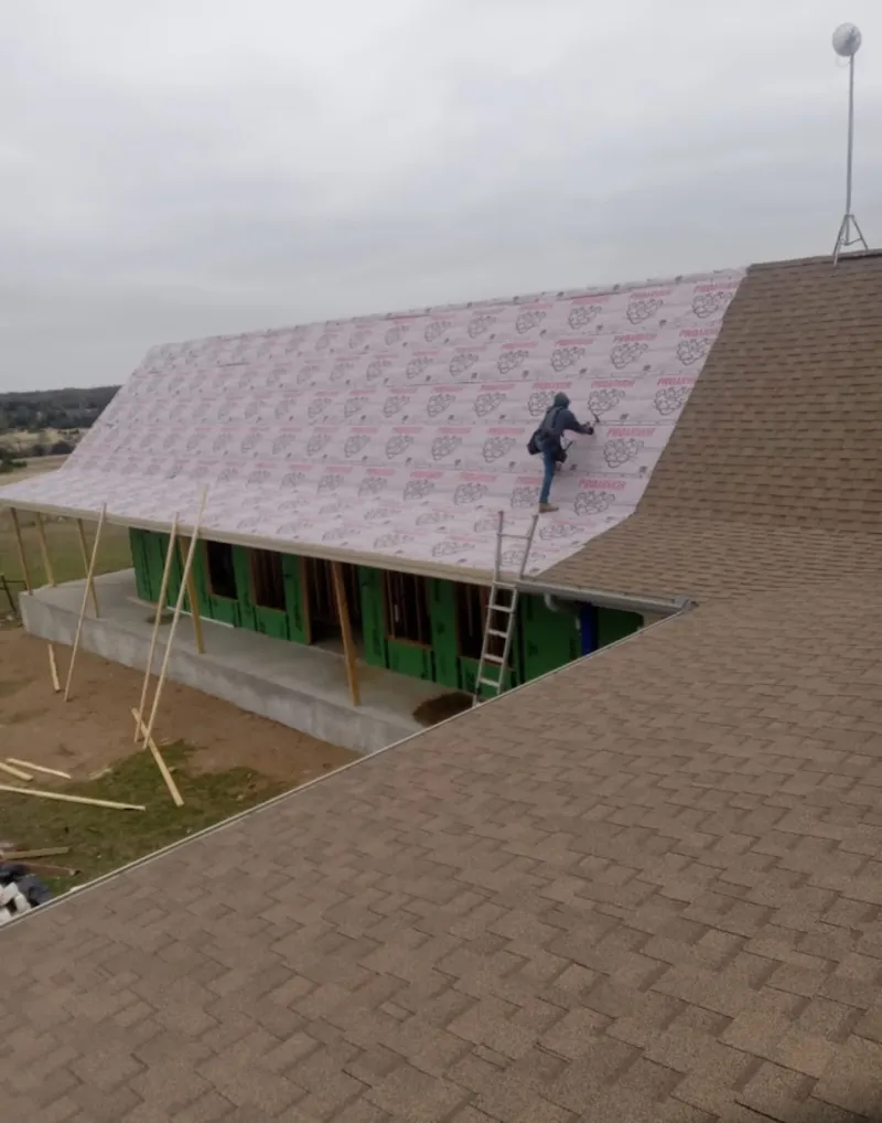 Worker preparing underlayment for a metal roof installation in Oak Grove